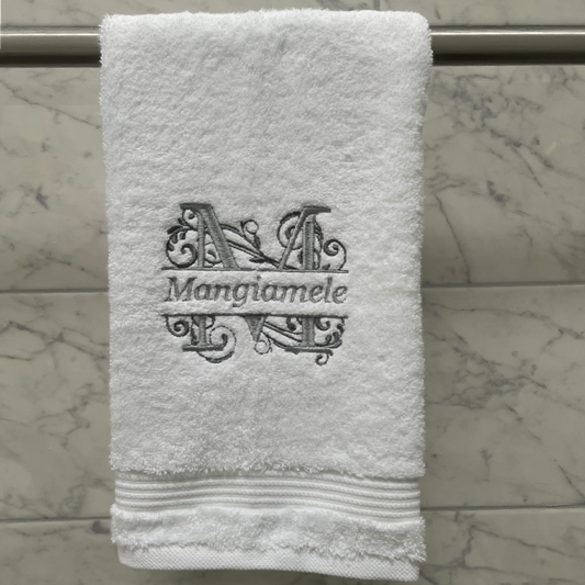 White towel with embroidered initials and name on a marble surface